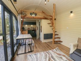 A compact living space with a wooden staircase and loft above a kitchen area at Binsey Lodge in Longlands near Caldbeck