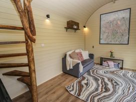 A room with a wooden spiral staircase a grey sofa with pillows a patterned rug a shelf with a wooden box and a large framed map on the wall at Binsey Lodge in Longlands near Caldbeck