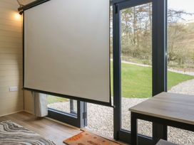 A room with a projector screen near glass doors that open to a garden at Binsey Lodge in Longlands near Caldbeck