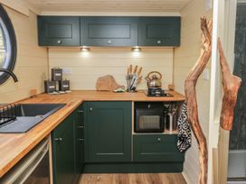 A kitchen with green cabinets wooden countertops a sink stove oven and kitchen utensils at Binsey Lodge in Longlands near Caldbeck