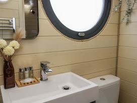 A bathroom sink with toiletries and a vase next to a round window at Binsey Lodge in Longlands near Caldbeck