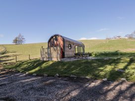 A small wooden cabin with a picnic table outside in a grassy field at Binsey Lodge in Longlands near Caldbeck