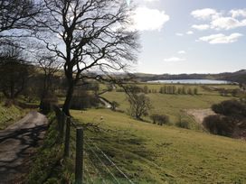 A rural landscape with a dirt road trees grazing sheep and a lake in the distance at Binsey Lodge in Longlands near Caldbeck