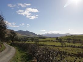 A rural road next to fields and hills under a blue sky at Binsey Lodge in Longlands near Caldbeck
