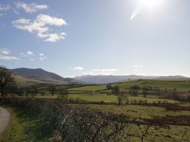 A rural landscape with green fields trees and mountains under a blue sky at Binsey Lodge in Longlands near Caldbeck
