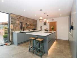 A kitchen with an island and stools at The Hay Barn in Huntley