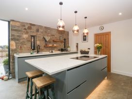 A kitchen with a large island and bar stools at The Hay Barn in Huntley