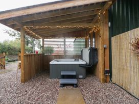 An outdoor area with a hot tub and wooden structure at The Hay Barn in Huntley