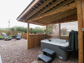 An outdoor area with a hot tub and seating at The Hay Barn in Huntley