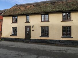 A house with a thatched roof and windows at Bridge Cottage in Budleigh Salterton