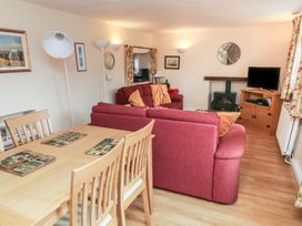 A living room with a sofa, table, and television at Bridge Cottage Budleigh Salterton
