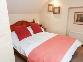 A bedroom with a bed and framed pictures at Bridge Cottage in Budleigh Salterton