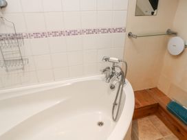 A bathroom with a bathtub and soap rack at Bridge Cottage in Budleigh Salterton