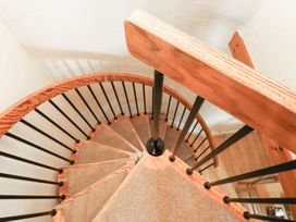 A spiral staircase with wooden handrail and metal railing at Bridge Cottage Budleigh Salterton