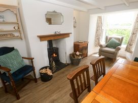 A living room with a fireplace and dining table at Greenways Perranporth