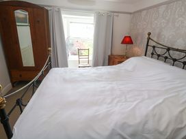 A bedroom with a bed, wardrobe, lamp, and chair at Greenways in Perranporth