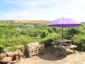 A garden with a purple umbrella and wooden table at Greenways in Perranporth