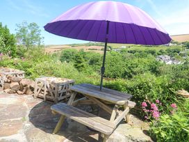 An outdoor seating area with a table and purple umbrella at Greenways in Perranporth