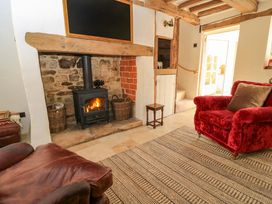 A living room with a wood stove and red sofa at 8 Gloucester Street in Winchcombe