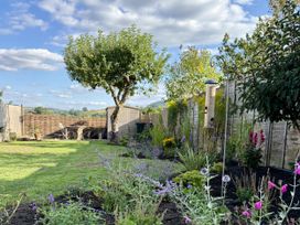 A garden with a tree and a bird feeder at The Garden Retreat in Winchcombe