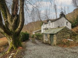 A house with a stone wall and tree in front at Brockstones in Grasmere