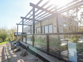 A wooden exterior patio with glass railing and plants at Bay View in Portreath