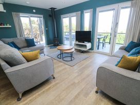 A living room with sofas cushions coffee tables tv and a stove at Bay View in Portreath