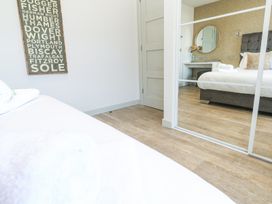 A bedroom with a bed and a mirror door wardrobe reflecting a vanity table with a round mirror and a bed at Bay View in Portreath
