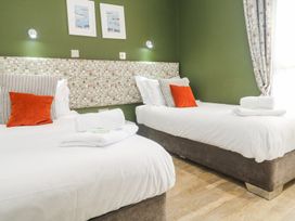 A bedroom with two single beds with white bedding and towels on each bed at Bay View in Portreath