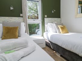 A bedroom with two single beds with patterned headboards and cushions by a window at Bay View in Portreath