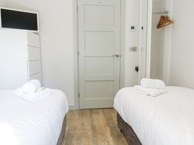 A bedroom with two beds a TV on a chest of drawers a door and a wall mirror at Bay View in Portreath