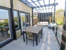 An outdoor patio with a dining table and chairs a seating area and plants at Bay View in Portreath