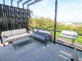 An outdoor patio with two grey sofas a metal coffee table potted plants and a barbecue grill at Bay View in Portreath
