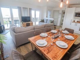 A living room with a dining area and kitchen cabinets at Bay View in Portreath