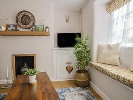 A living room with a shelf, television, plant, and table at 6 Bedford Place in Bridport
