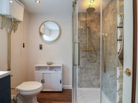 A bathroom featuring a toilet, sink, shower, and mirror at 6 Bedford Place in Bridport