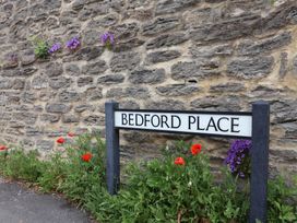 A street sign with the name Bedford Place beside a stone wall in Bridport