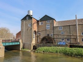 A building with a water wheel next to a bridge in Bridport at 6 Bedford Place