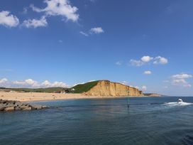 A beach with cliffs and a boat on the water at 6 Bedford Place in Bridport