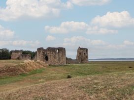 Ruins of a historical structure in a grassy field near water at 5 Marsh Lane in Flint