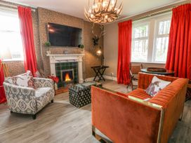 A living room with fireplace television patterned armchair and orange sofa at Waterside Lodge near Annan