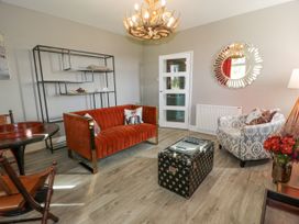 A living room with an orange sofa a patterned armchair a black trunk coffee table and an antler chandelier at Waterside Lodge near Annan