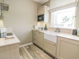 A kitchen with beige cabinets a white farmhouse sink microwave toaster and window at Waterside Lodge near Annan
