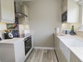 A kitchen with oven, toaster, scale, microwave, sink, and utensils at Waterside Lodge near Annan