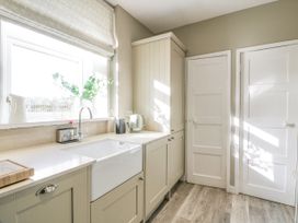 A kitchen with a sink and cabinets next to two white doors at Waterside Lodge near Annan