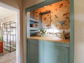 A built-in cabinet area with a wooden countertop a lamp and flowers on the counter at Waterside Lodge near Annan