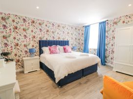 A bedroom with a blue bed frame white bedding floral wallpaper blue curtains and white furniture at Waterside Lodge near Annan