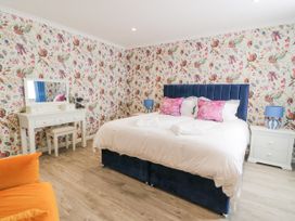 A bedroom with a bed a dressing table and an orange chair at Waterside Lodge near Annan