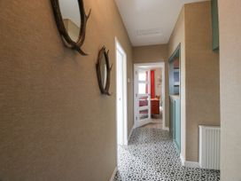 A hallway with patterned floor tiles mirrors on the wall and a door leading to a room with red curtains at Waterside Lodge near Annan