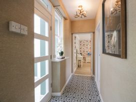 A hallway with patterned floor tiles a white door and a floral wallpaper room at Waterside Lodge near Annan